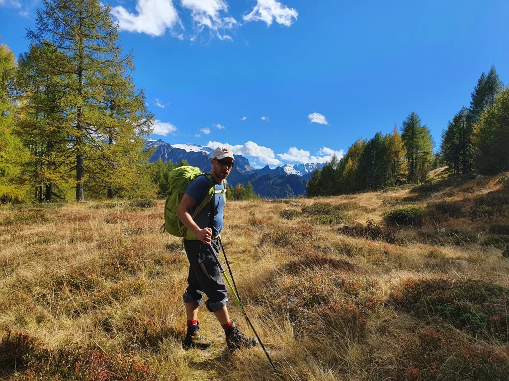 Wanderer auf einer herbstlichen Alpwiese vor einem Bergmassiv im Tessin